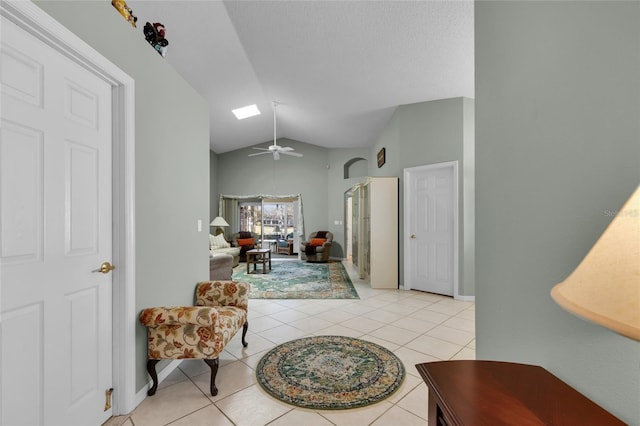 corridor featuring vaulted ceiling with skylight, light tile patterned floors, and a textured ceiling