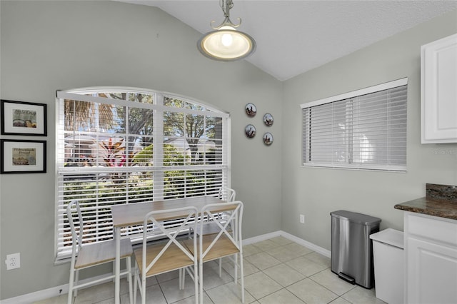 tiled dining area featuring lofted ceiling and a textured ceiling