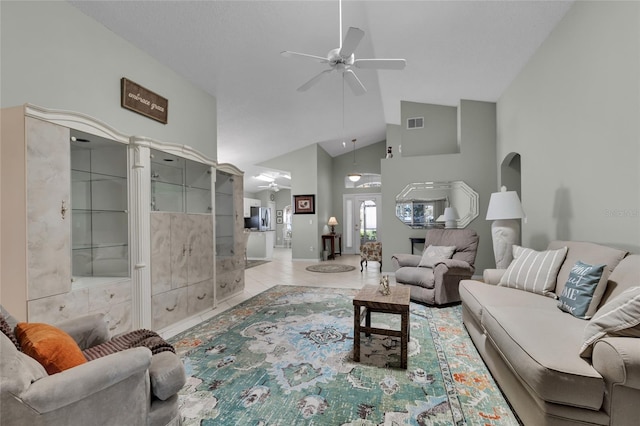 tiled living room with ceiling fan and high vaulted ceiling