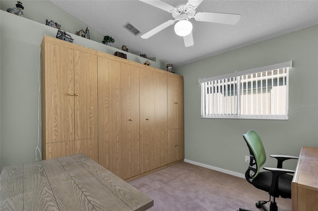 office space featuring light carpet, ceiling fan, and a textured ceiling