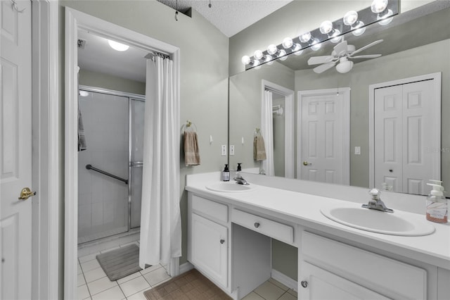 bathroom featuring a shower with shower door, tile patterned flooring, vanity, ceiling fan, and a textured ceiling