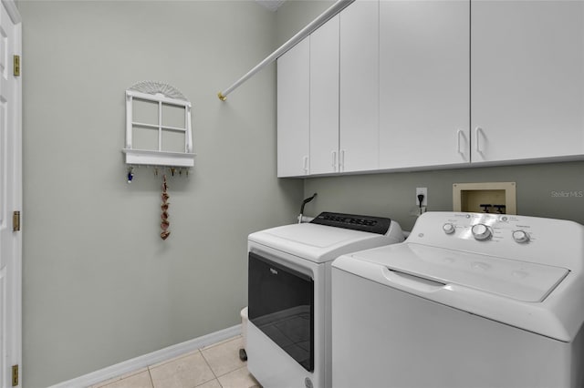 laundry room featuring washer and dryer, cabinets, and light tile patterned flooring