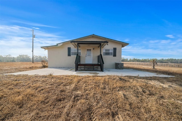 view of front of home featuring a rural view, central AC unit, and a patio