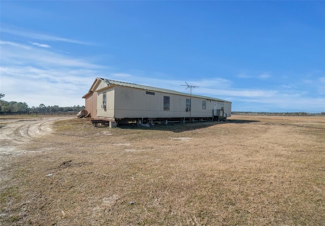 view of front of house featuring a front lawn, metal roof, and a rural view