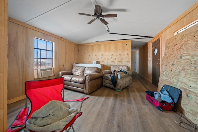 living room with a ceiling fan, vaulted ceiling, wood walls, wood finished floors, and cooling unit