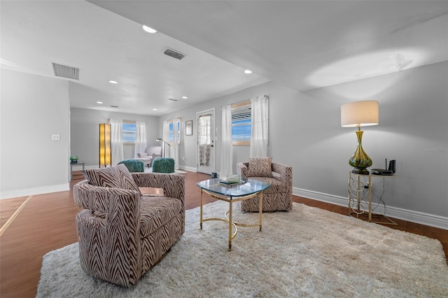 living room featuring wood finished floors, visible vents, and baseboards