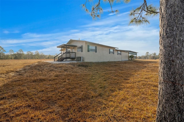 exterior space featuring central AC, a lawn, and a rural view