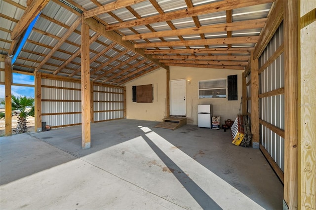 miscellaneous room with lofted ceiling, metal wall, and unfinished concrete floors