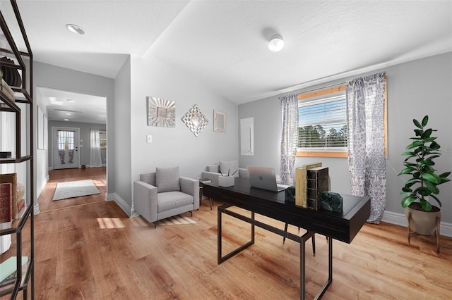 office space featuring lofted ceiling, light wood-type flooring, and baseboards