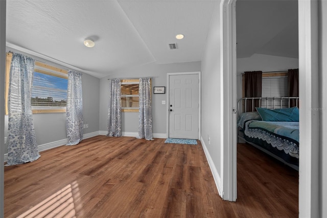 entrance foyer with visible vents, vaulted ceiling, baseboards, and wood finished floors