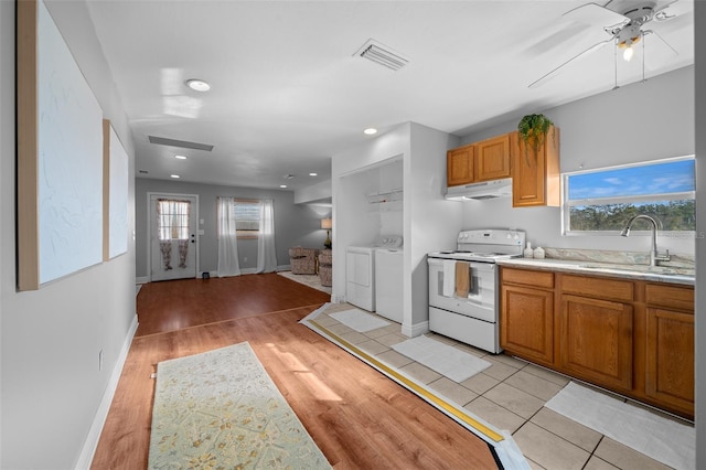 kitchen featuring visible vents, light countertops, under cabinet range hood, washing machine and dryer, and white range with electric cooktop