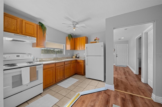 kitchen featuring light tile patterned floors, under cabinet range hood, white appliances, a sink, and light countertops