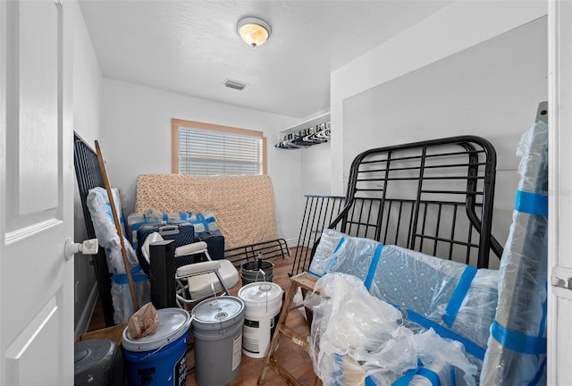 bedroom with visible vents, a textured ceiling, and wood finished floors