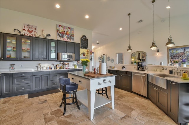 kitchen featuring stainless steel appliances, sink, a kitchen bar, and decorative light fixtures