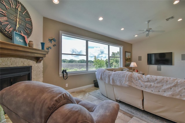 living room featuring ceiling fan, lofted ceiling, and a stone fireplace