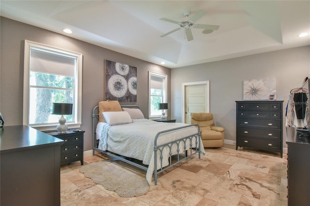 bedroom featuring multiple windows, a tray ceiling, and ceiling fan