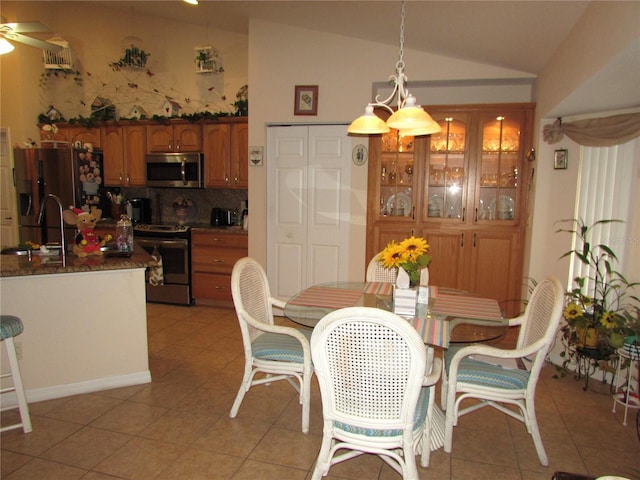 tiled dining area featuring ceiling fan, vaulted ceiling, and sink