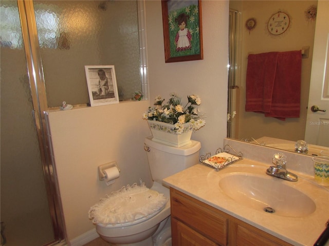 bathroom featuring toilet, vanity, and a shower with shower door