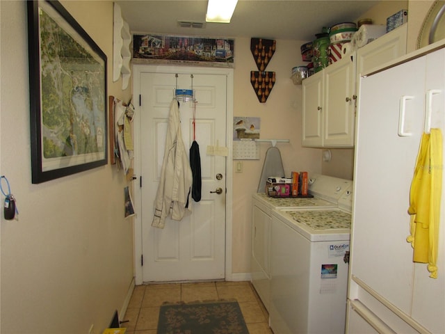 clothes washing area with cabinets, light tile patterned flooring, and washer and clothes dryer