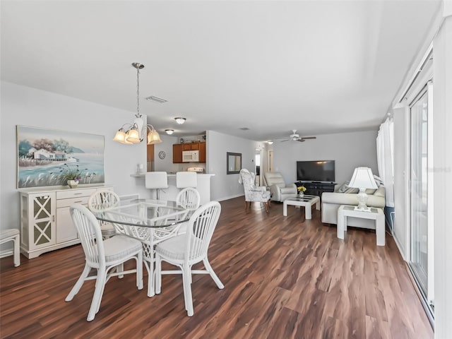 dining area featuring dark wood-type flooring and ceiling fan with notable chandelier