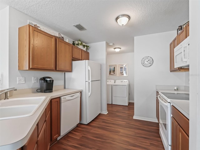 kitchen with dark wood-type flooring, sink, a textured ceiling, white appliances, and washer and clothes dryer