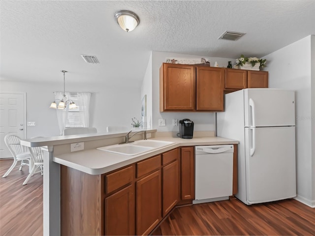 kitchen featuring sink, hanging light fixtures, kitchen peninsula, dark wood-type flooring, and white appliances