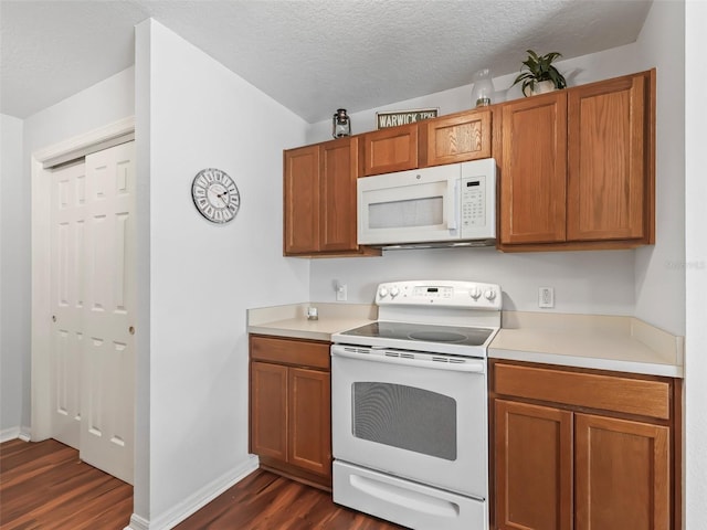 kitchen featuring dark hardwood / wood-style flooring, white appliances, and a textured ceiling