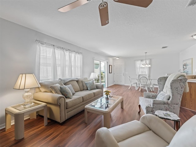 living room featuring wood-type flooring, ceiling fan with notable chandelier, and a textured ceiling