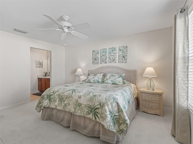 carpeted bedroom with ensuite bathroom and ceiling fan