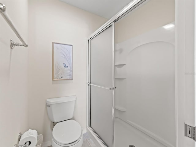 bathroom featuring a shower with door and toilet