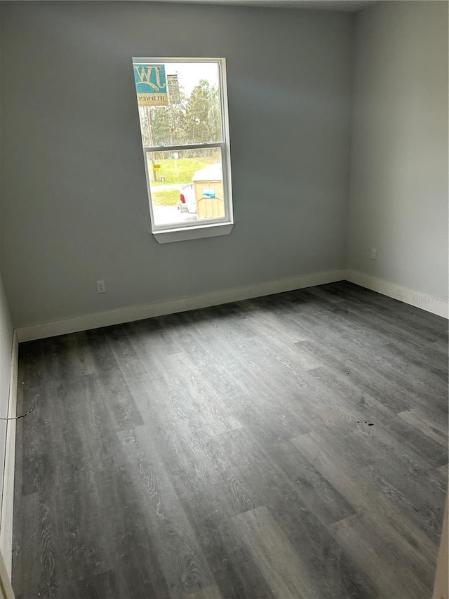 spare room featuring baseboards and wood finished floors
