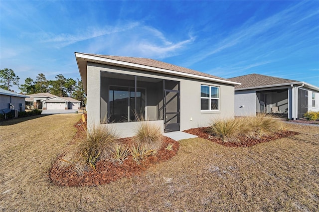 back of house featuring a lawn and a sunroom