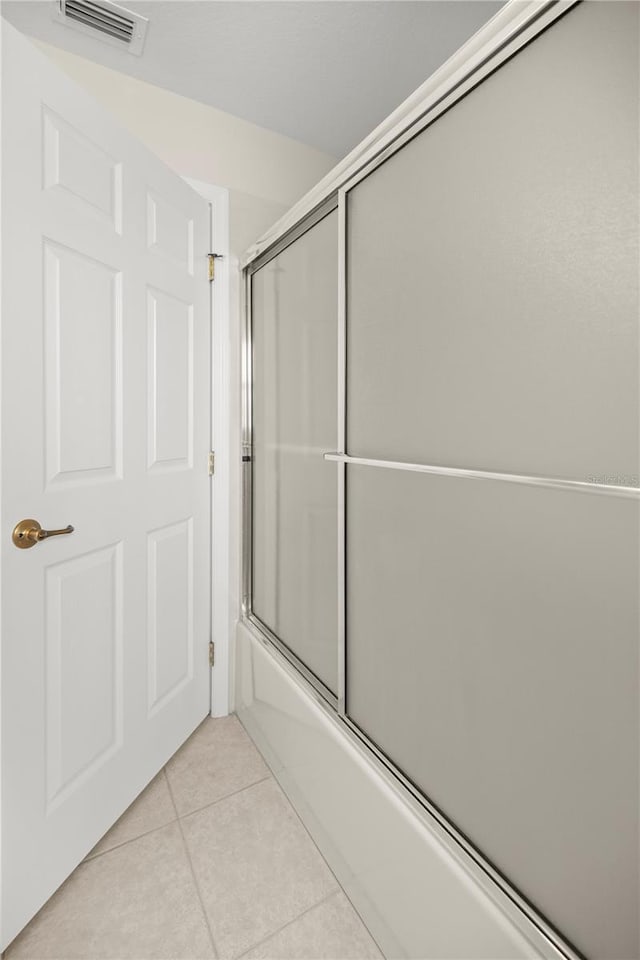 bathroom featuring bath / shower combo with glass door and tile patterned floors