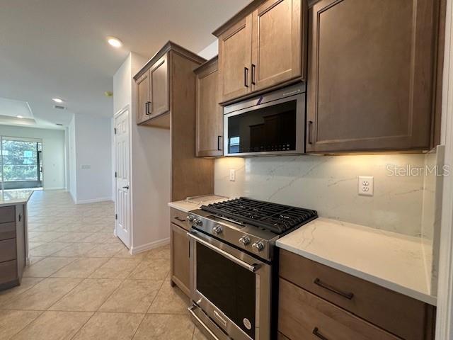 kitchen with appliances with stainless steel finishes, light tile patterned floors, and backsplash