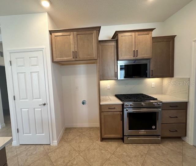 kitchen with light tile patterned flooring, appliances with stainless steel finishes, and decorative backsplash