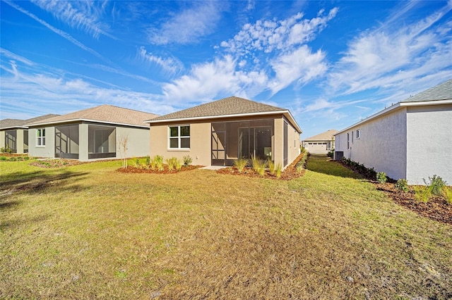 rear view of house featuring a sunroom, cooling unit, and a lawn