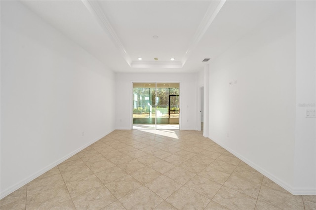 tiled spare room with crown molding and a tray ceiling