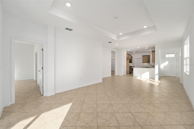 unfurnished living room featuring crown molding and a tray ceiling