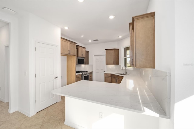 kitchen with sink, light stone counters, light tile patterned floors, kitchen peninsula, and stainless steel appliances