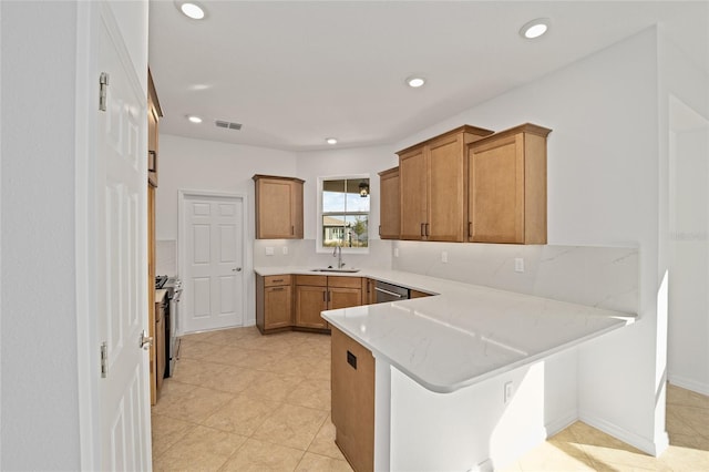 kitchen featuring sink, light stone counters, appliances with stainless steel finishes, a kitchen breakfast bar, and kitchen peninsula