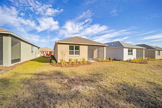 back of property featuring a lawn and a sunroom