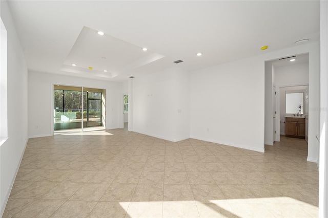 empty room with sink and a tray ceiling