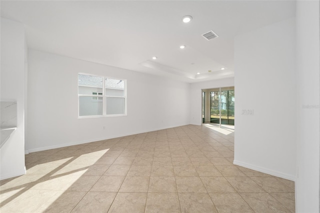 unfurnished room with light tile patterned floors and a raised ceiling