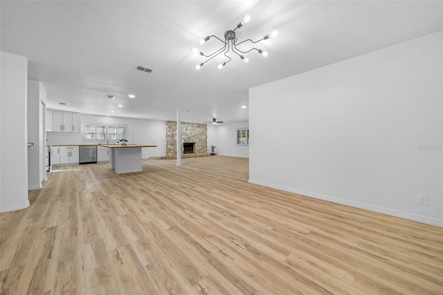 unfurnished living room with a fireplace, light hardwood / wood-style floors, and a textured ceiling