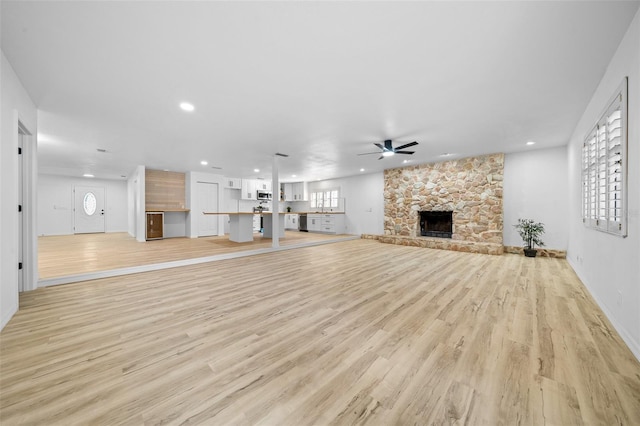 unfurnished living room with ceiling fan, a fireplace, and light hardwood / wood-style flooring