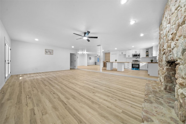 unfurnished living room featuring ceiling fan, sink, and light hardwood / wood-style floors