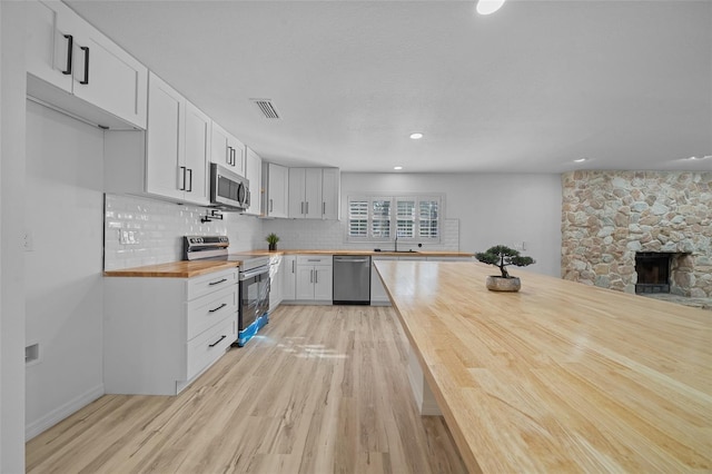 kitchen with sink, butcher block countertops, appliances with stainless steel finishes, decorative backsplash, and white cabinets