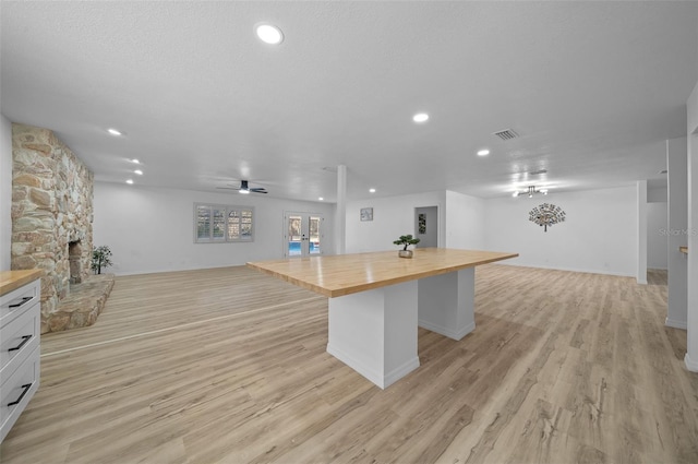 kitchen with a kitchen bar, butcher block countertops, a fireplace, light hardwood / wood-style floors, and white cabinets