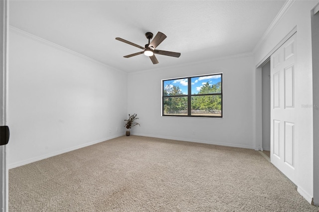 spare room with carpet floors, ornamental molding, and ceiling fan