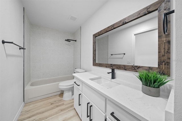 full bathroom with vanity, hardwood / wood-style floors, tiled shower / bath, and toilet